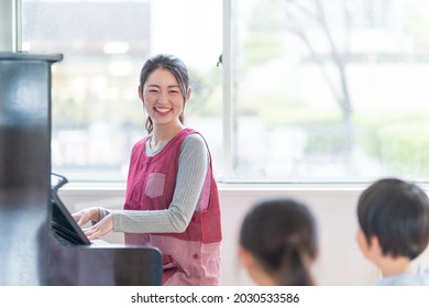 A nursery teacher playing the piano and a kindergarten singing - Shutterstock ID 2030533586
