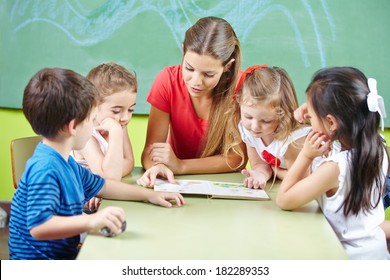 Nursery Teacher Reading Book Aloud To Children In A Kindergarten Group