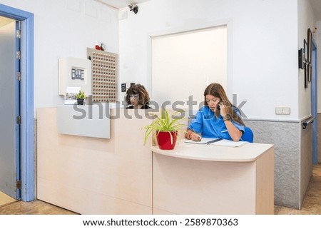 Nurses efficiently handling administrative tasks at a geriatric nursing home reception desk, showcasing a caring and professional environment