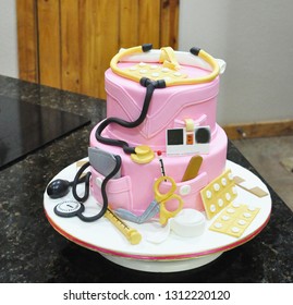 Nurses graduation cake with pink marshmallow fondant and edible cake toppers.