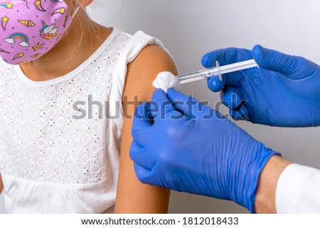 NURSE'S HANDS INJECTING COVID VACCINE TO A CHILD WITH MASK. CORONAVIRUS VACCINATION CONCEPT. INJECTION AND IMMUNIZATION. MUTATIONS AND NEW STRAINS. OMICRON SUB VARIANT CENTAURUS. FLU SHOT.
