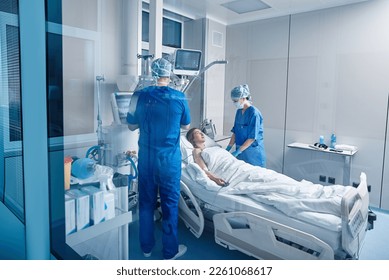 Nurses in intensive care unit of hospital checking vitals of hospitalized female patient. ICU