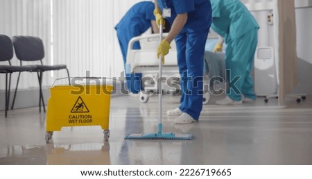 Nurses mopping floor and making bed in empty hospital ward. Medical staff in uniform wiping floor and cleaning intensive care unit in modern clinic