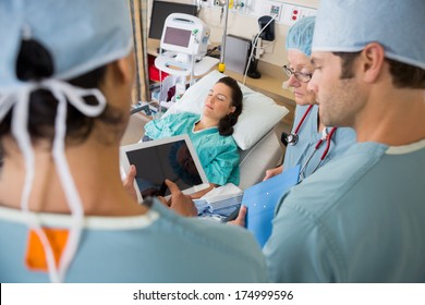 Nurses in Post op unit discussing patient's medical chart - Powered by Shutterstock