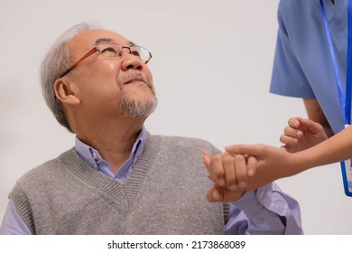Nursing aide holding and patting winkled hand of a patient.Domiciliary care for sick elderly.