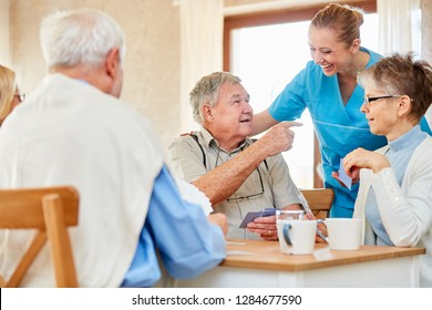 Nursing Lady Has Fun With A Group Of Seniors Playing Cards In The Nursing Home