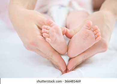 Nursing mother holding keeping legs of her infant