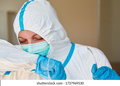 Nursing staff in clinic or home in protective clothing coughs in armpit during coronavirus epidemic - Shutterstock ID 1737969530