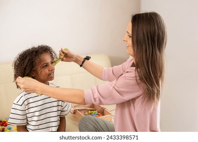 A nurturing scene unfolds as a mother carefully styles her African American daughter's curly hair, their bond evident in their joyful expressions. High quality photo - Powered by Shutterstock