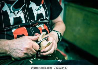 Nusnas, Dalarna / Sweden - august 06 2017: Hands of an artist carving traditional Dala Horse in Nils Olsson Hemslojd manufacture in Nusnas