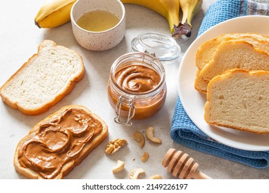 Nut Butter Toast With Bananas And Honey On Light Table. Walnut, Hazelnut And Cashew Nut Spread In Glass Jar. Homemade Breakfast Sandwich. Healthy Food Concept.