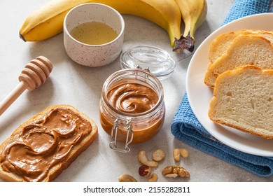 Nut Butter Toast With Bananas And Honey On Light Table. Walnut, Hazelnut And Cashew Nut Spread In Glass Jar. Homemade Breakfast Sandwich. Healthy Food Concept.