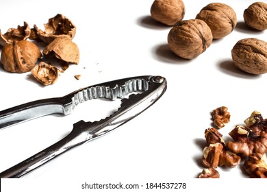 Nutcracker metal, on a light background, with walnuts, shells and peeled. A tool for cleaning nuts.