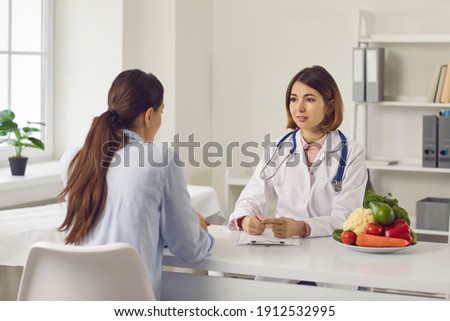Nutrition expert talking to client about health problems and importance of eating healthy food. Doctor, nutritionist or dietitian discussing treatment with young woman and making individual diet plan