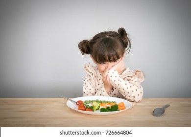 Nutrition & healthy eating habits for kids concept. Children do not like to eat vegetables. Little cute kid half race girl refuse to eat healthy vegetables. - Shutterstock ID 726664804