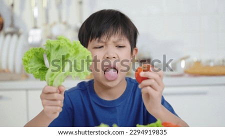 Nutrition and healthy eating habits for kids concept. Asian little boy looking with disgust on vegetable, refusing to eat