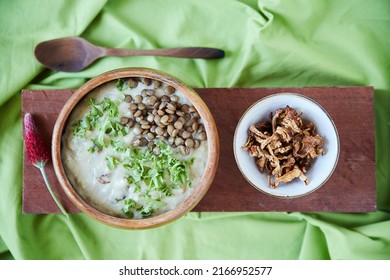 Nutrition Isnt About Just Eating, Its About Learning To Live. Overhead Shot Of A Creamy Legume And Lentil Soup Garnished With Chopped Kale With A Ramekin Of Dried Mushrooms On A Wooden Board.