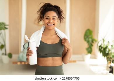 Nutrition for sport and exercise. Happy african american woman with white towel on neck holding shaker with protein, smiling at camera after domestic workout - Powered by Shutterstock