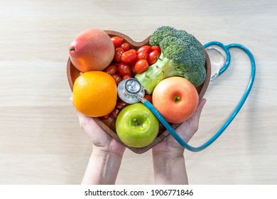 Ernährung für Wellness im Herzen durch Cholesterinernährung und gesunde Ernährung mit sauberem Obst und Gemüse in der Herzschale von Ernährungswissenschaftler und Arzt empfohlen für das Wohlbefinden der Patienten