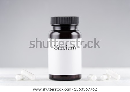 nutritional supplement calcium bottle and capsules on gray