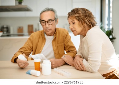 Nutritional supplement. European senior spouses reading prescriptions for new pills or vitamins, sitting at table in kitchen interior, copy space - Powered by Shutterstock