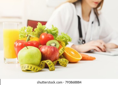 Nutritionist desk with healthy fruit, juice and measuring tape. Dietitian working on diet plan. Weight loss and right nutrition concept