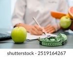 Nutritionist desk with healthy fruits, juice and measuring tape. Unrecognizable dietitian working on diet plan for overweight patient . Weight loss and right nutrition concept, selective focus