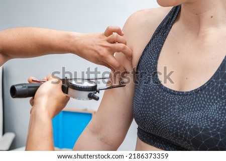 Nutritionist doctor measuring woman's body fat layer with caliper, nutritionist tool, indoors, closeup