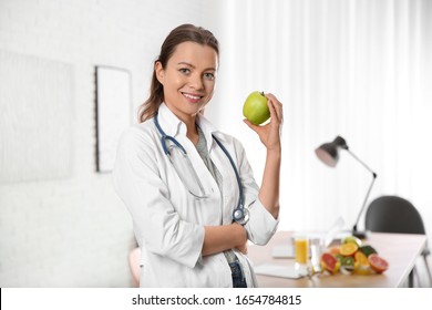 Nutritionist with fresh apple in her office