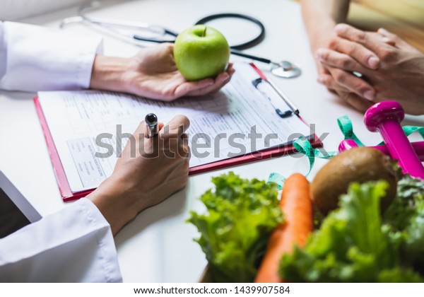 Nutritionist giving\
consultation to patient with healthy fruit and vegetable, Right\
nutrition and diet\
concept