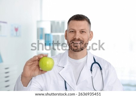 Nutritionist with green apple and stethoscope in clinic