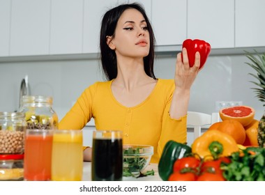  
Nutritionist.woman Thinking About Healty Food,diet Holding  Red Sweet Pepper Sitting In The Kitchen