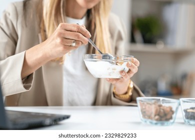 Nutritious meal at work. Woman indulges in a satisfying bowl of muesli and creamy yogurt, fueling her body with a balanced and energizing breakfast
