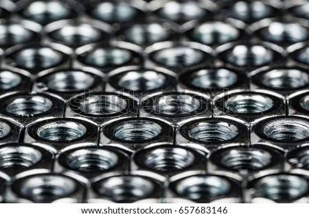 Nuts and bolts metal fasteners. Hexagon metal nuts arranges in a tessellation macro, with dramatic lighting to illustrate engineering or construction expertise.