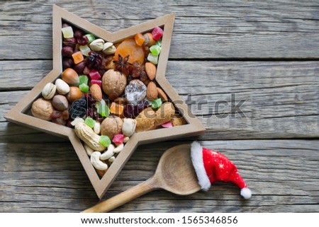 Nuts and dried fruits mix for Christmas with spoon and Santa's hat on wooden boards