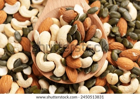 Nuts with pumpkin seeds in woodenware. Various mixed ingredients. Green dry kernels on a wooden rustic spoon with almonds and cashews