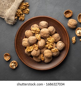 Nuts. Walnut kernels and whole walnuts on dark stone table. Top view, flat lay.
