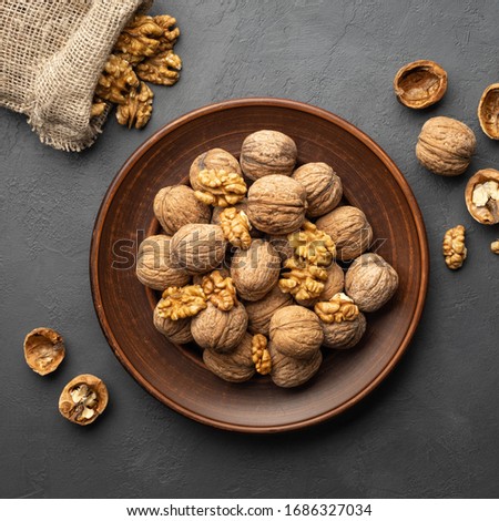 Nuts. Walnut kernels and whole walnuts on dark stone table. Top view, flat lay.