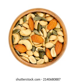 Nut-seed mix, in a wooden bowl. Unsalted and crunchy mix of roasted peanuts, cashews, pumpkin seeds and almonds. Close-up, from above, isolated on white background, macro food photo.