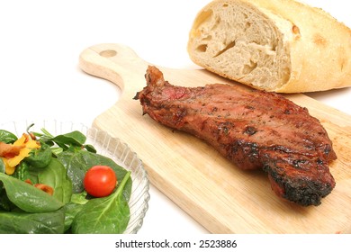 NY Strip Steak On Cutting Board With Salad & Bread