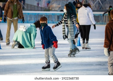 NY, NY, USA - Jan. 22, 2021: Kids Learning To Skate Wearing Protective Masks On Ice Rink With Parents During Pandemic