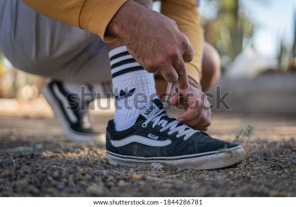 NYC/USA - October 12, 2020; Man tying the\
shoelaces of a black Vans in a public car. He was wearing also\
white Adidas socks and a Gray Nike\
shorts.