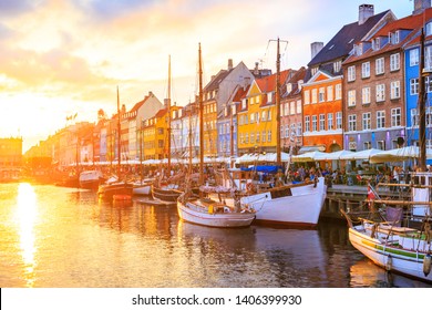 Nyhavn Canal In Copenhagen, Denmark - Row Of Colorful Houses And Boats On The Waterfront Under Sunset Colors In The Sky. The Most Famous Landmark In The City Lined With Restaurants And Cafes.