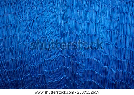 Nylon knitted rope. Blue colored nylon knitted rope. Fishing net knitted with nylon thread.
Blue fishing net threads stacked background.
