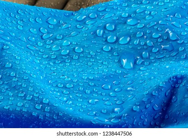 Nylon waterproof fabric background. Texture of blue woven synthetic waterproof clothing. Waterproof fabric with waterdrops. Rain Drops on Water Resistant Textile waterproof coating background.