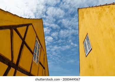 Nysted, Denmark - 11 June, 2021: half-timbered yellow houses in stark contrast under a blue sky with cumulus clouds