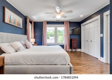 OAK PARK, IL, USA - JUNE 2, 2020: A Classic Blue Master Bedroom With Pink Curtains Hanging To The Hardwood Floors.