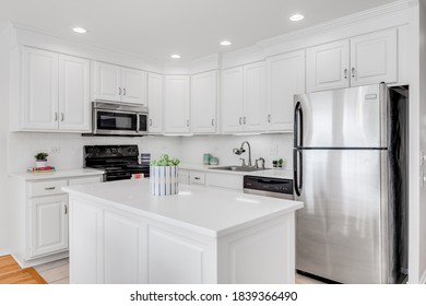 OAK PARK, IL, USA - JUNE 17, 2020: An All White Kitchen With Stainless Steel Appliances And Small Decorations On The Counter Tops.