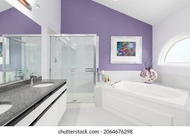 OAK PARK, IL, USA - MAY 26, 2021: A Primary Bathroom With A Dark Grey Marble Countertop, White Vanity Cabinet, Standup Shower, And Jacuzzi Tub.