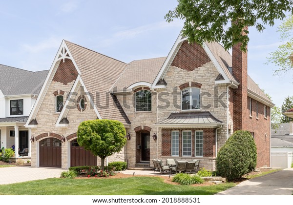 OAK PARK, IL,\
USA - MAY 23, 2021: A full masonry home with a two car garage,\
front yard patio, brick paver driveway, and a mixture of brick and\
stone throughout the\
exterior.